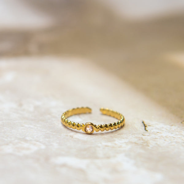 Gedraaide gouden ring met een roze glitter steen