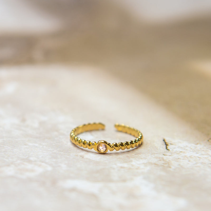 Gedraaide gouden ring met een roze glitter steen